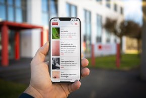 News Handy in der Hand mit news von WEPA in Nahaufnahme. Das Handy wird vor das WEPA Gebäude gehalten