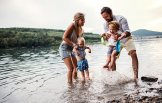 Eine Familie ( Frau, Mann und zwei Kinder ) spielen im seichten Flusswasser