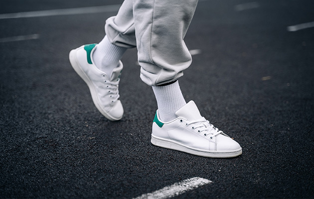 Tipps gegen Zecken Die Beine und Schuhe eines Mannes sind zu sehen. Dieser trägt hohe weiße Socken und sportliche Schuhe